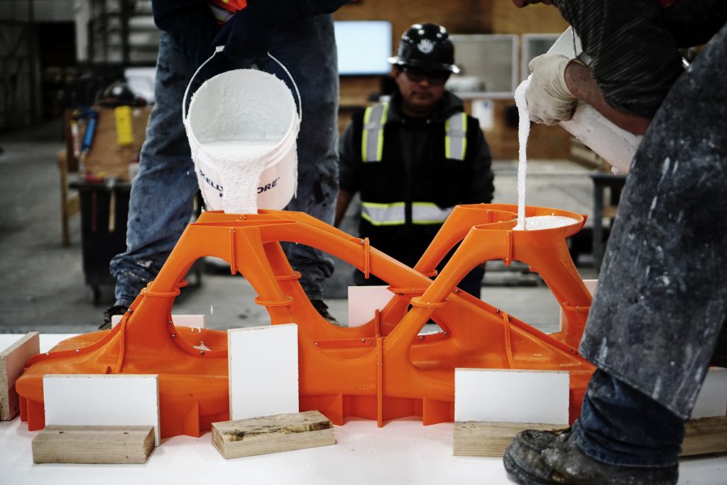 Filling the 3D printed mold with white concrete. Photo via Slicelab.