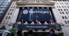 Traders looking up at a Markforged sign outside the NYSE.
