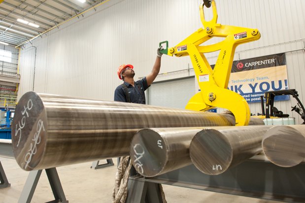 木匠员工使用升降机在阿拉巴马州的设施中移动实心钢合金棒。通过木匠技术照片