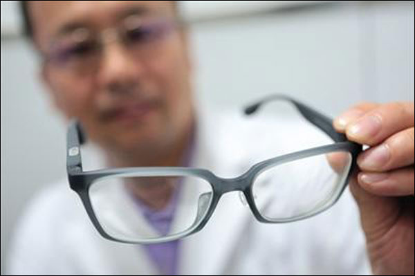 Dr. Song Hongxin holding a pair of 3D printed glasses. Photo via Beijing News