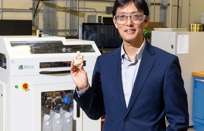 Ornl科学家Tomonori Saito展示了使用小说粘合剂印刷的沙堡3D。